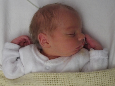 Another baby, also lying in a cot.